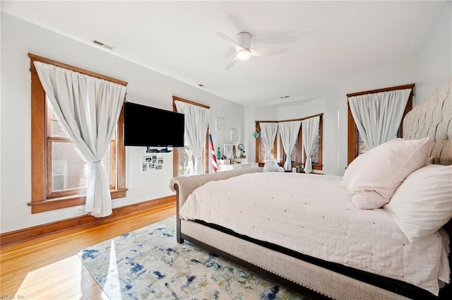 bedroom featuring ceiling fan, visible vents, baseboards, and wood finished floors