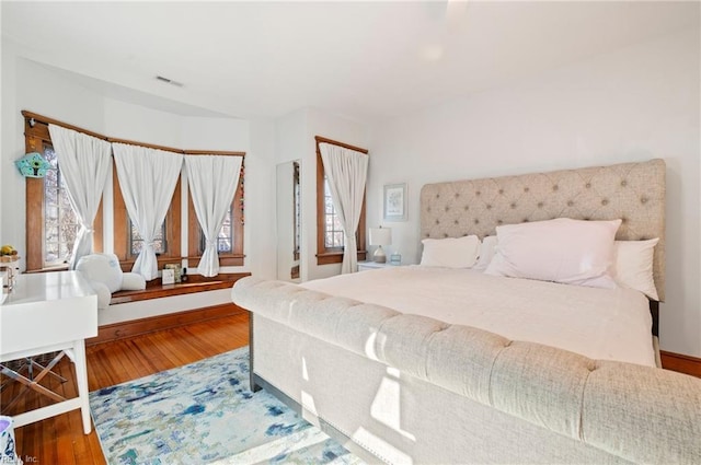 bedroom featuring visible vents, baseboards, and wood finished floors