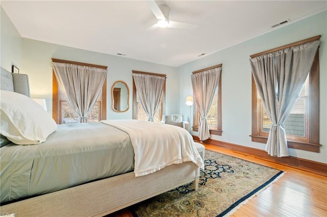 bedroom with visible vents, baseboards, a ceiling fan, and wood finished floors