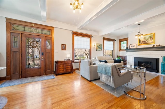 living area with beamed ceiling, plenty of natural light, light wood-style floors, and a fireplace with flush hearth