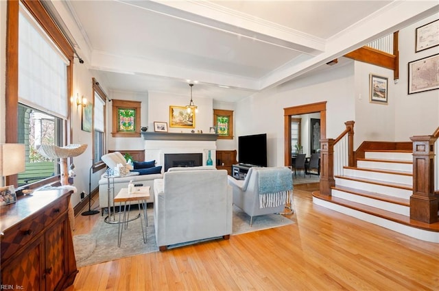 living room with beam ceiling, stairway, a healthy amount of sunlight, and a fireplace