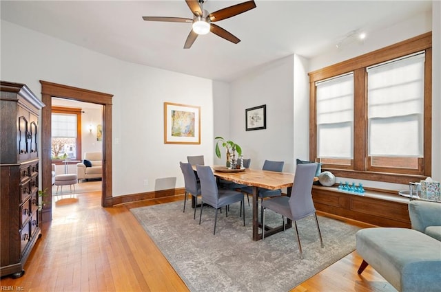 dining area with light wood-type flooring, baseboards, and ceiling fan