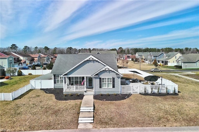 view of front facade with a residential view, a porch, a fenced backyard, and a front yard