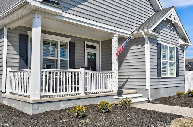 doorway to property with covered porch and roof with shingles