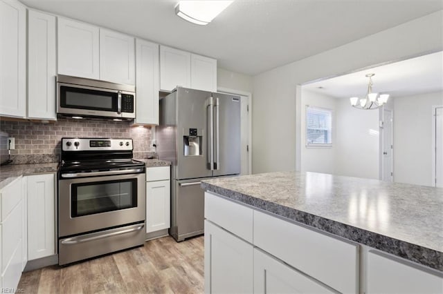 kitchen featuring a notable chandelier, light wood-style flooring, backsplash, stainless steel appliances, and white cabinets