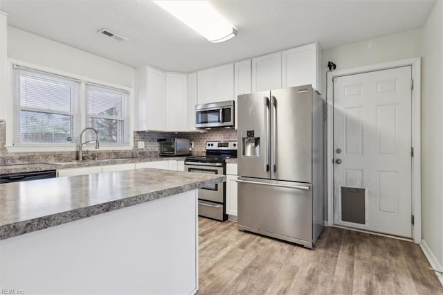 kitchen featuring visible vents, a sink, decorative backsplash, appliances with stainless steel finishes, and white cabinetry