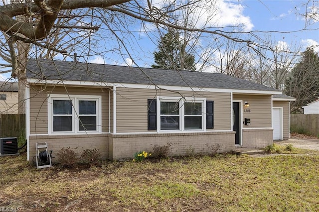 single story home featuring brick siding, a shingled roof, fence, central AC unit, and driveway