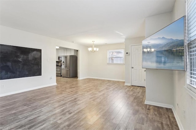 unfurnished living room with baseboards, wood finished floors, a chandelier, and a mountain view