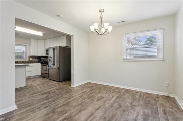 kitchen with white cabinetry, wood finished floors, a chandelier, and stainless steel appliances