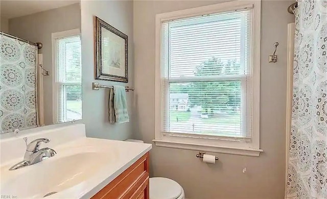 full bath with curtained shower, vanity, and toilet