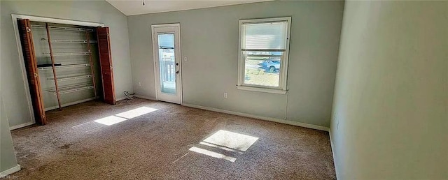 unfurnished bedroom with carpet, baseboards, vaulted ceiling, and a closet