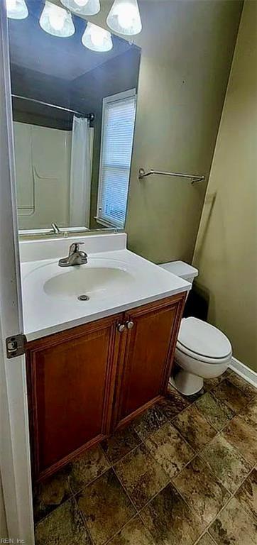 full bath featuring toilet, baseboards, a shower with shower curtain, and vanity