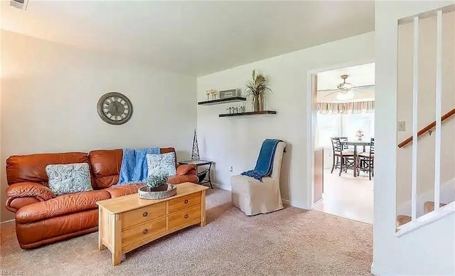 living room with stairs, visible vents, and light colored carpet