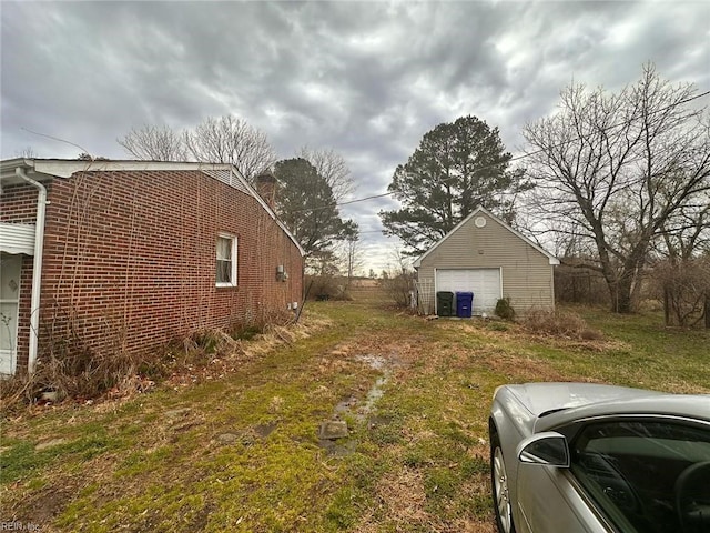 view of yard with a garage, driveway, and an outdoor structure
