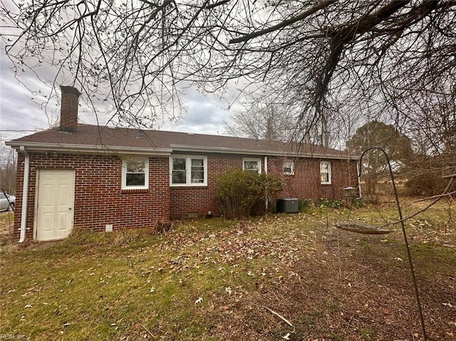 back of property with a chimney, cooling unit, and brick siding