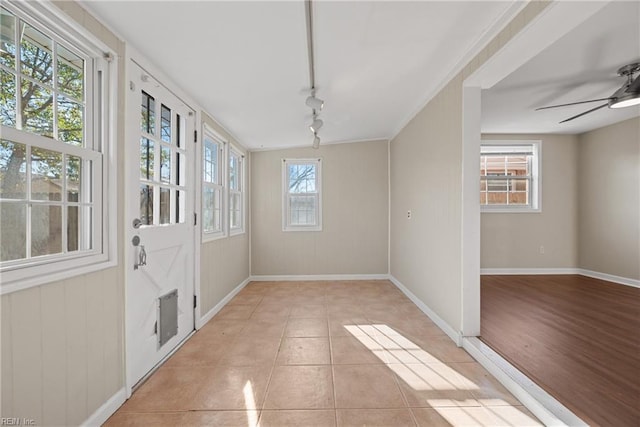 interior space with light tile patterned floors, a ceiling fan, rail lighting, and baseboards