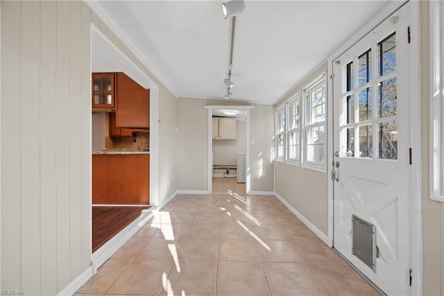 interior space with light tile patterned floors, rail lighting, and baseboards