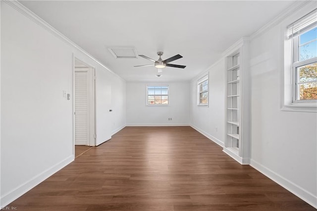 unfurnished room with attic access, baseboards, a ceiling fan, dark wood-style flooring, and crown molding