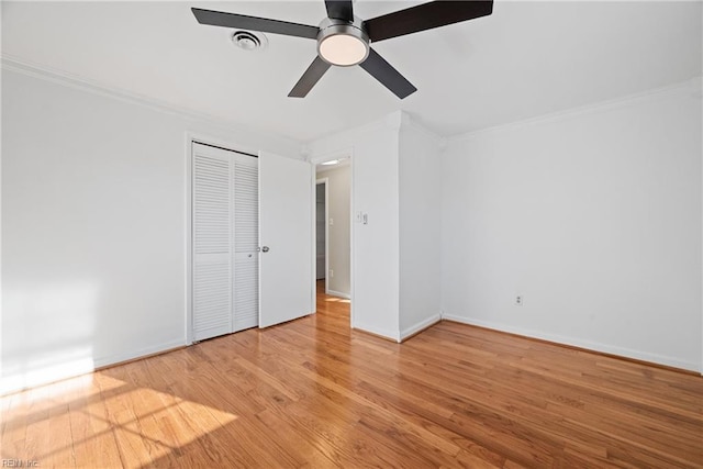 unfurnished bedroom featuring baseboards, visible vents, ornamental molding, wood finished floors, and a closet