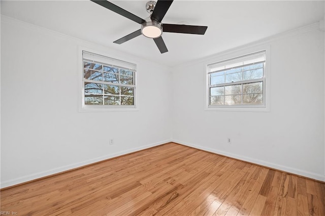 spare room featuring ornamental molding, light wood-style flooring, baseboards, and a ceiling fan