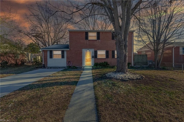 view of front of property featuring a yard, brick siding, and fence