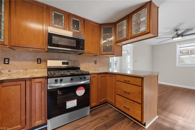 kitchen featuring a peninsula, appliances with stainless steel finishes, decorative backsplash, and brown cabinets