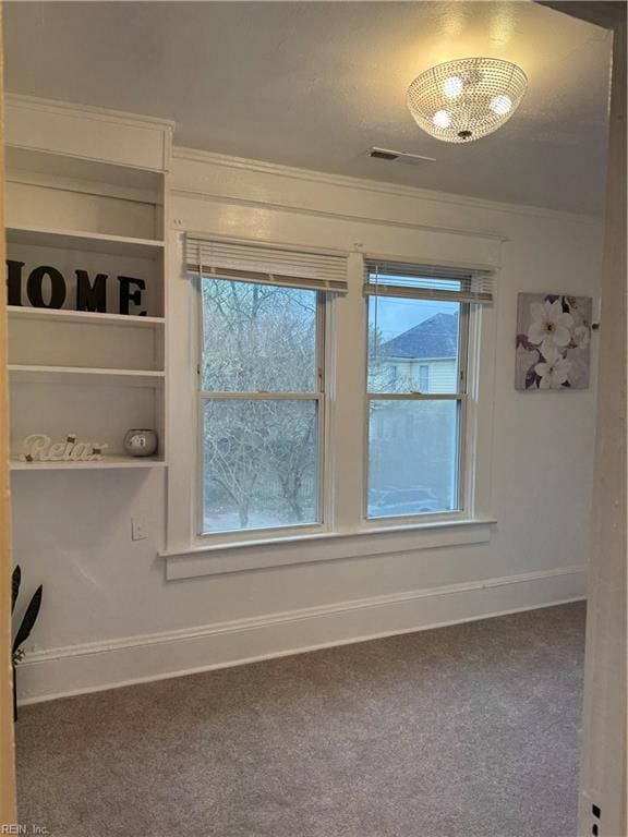 spare room featuring carpet flooring, visible vents, baseboards, and ornamental molding