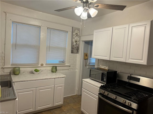 kitchen featuring tasteful backsplash, white cabinets, appliances with stainless steel finishes, and light countertops