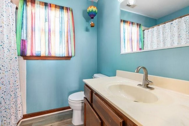 full bathroom with toilet, curtained shower, wood finished floors, baseboards, and vanity