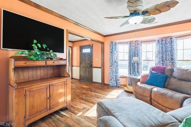 living area featuring a wealth of natural light, a ceiling fan, wood finished floors, and crown molding