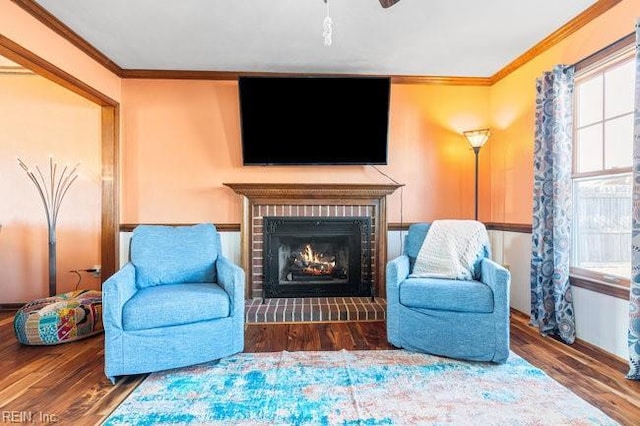 living area featuring a brick fireplace, wood finished floors, and crown molding