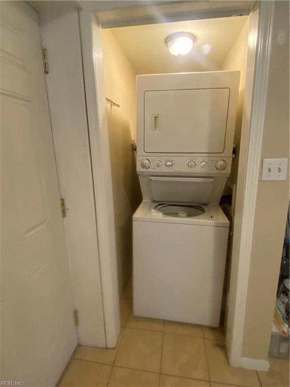 clothes washing area featuring laundry area, light tile patterned floors, and stacked washer / drying machine