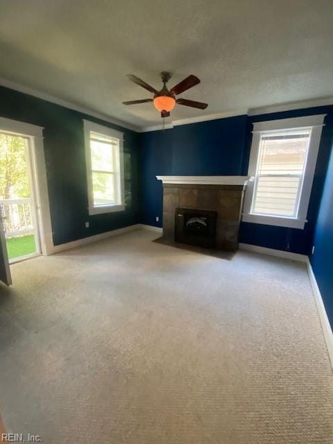 unfurnished living room with a fireplace with flush hearth, ornamental molding, a ceiling fan, baseboards, and light colored carpet