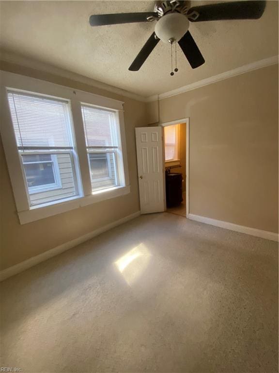 unfurnished bedroom with ceiling fan, baseboards, ornamental molding, light carpet, and a textured ceiling