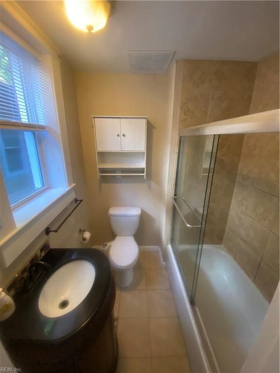 full bathroom featuring tile patterned floors, toilet, bath / shower combo with glass door, and a sink