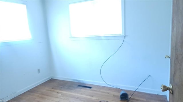 unfurnished room featuring wood finished floors, visible vents, and baseboards