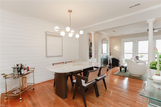 dining area with visible vents, ornamental molding, a ceiling fan, light wood-style floors, and ornate columns