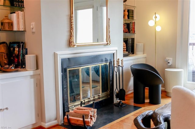 living area with a fireplace with flush hearth and wood finished floors