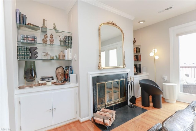 living room featuring a fireplace with flush hearth, visible vents, baseboards, and light wood-style floors