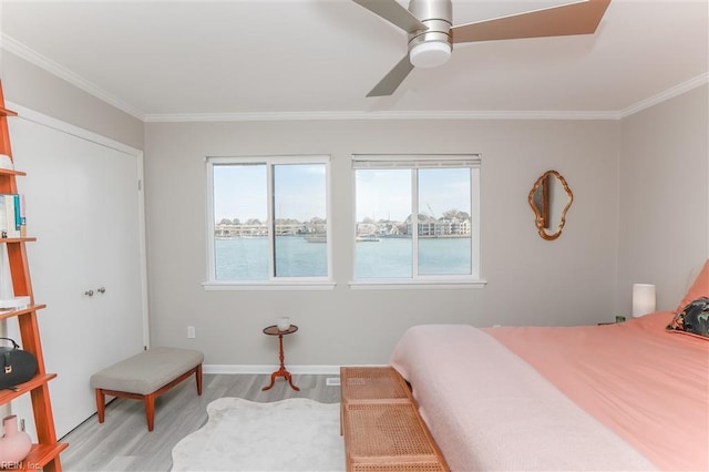 bedroom featuring baseboards, a ceiling fan, light wood-style flooring, and crown molding