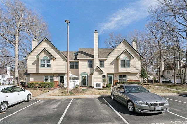 view of front of house featuring a chimney and uncovered parking