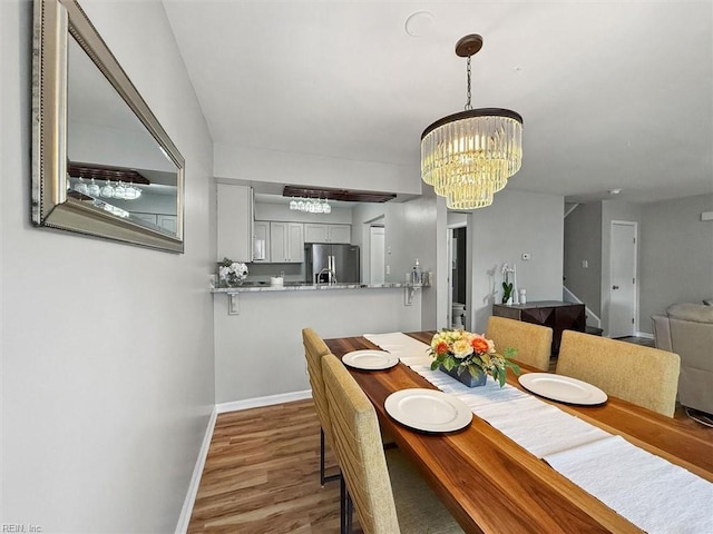 dining area with a chandelier, baseboards, and wood finished floors