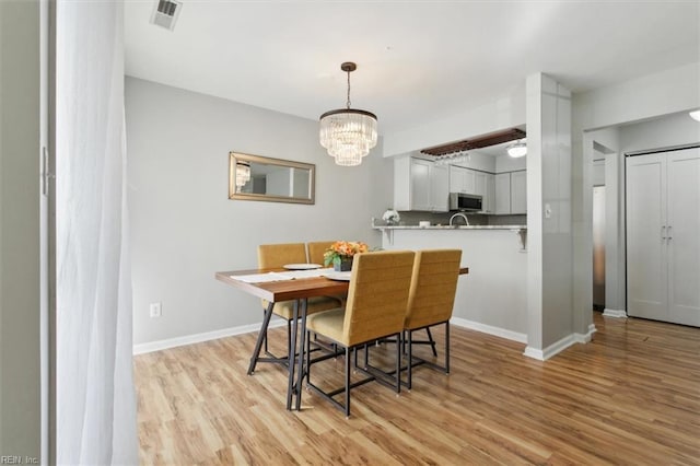 dining space with a notable chandelier, visible vents, baseboards, and light wood-style floors