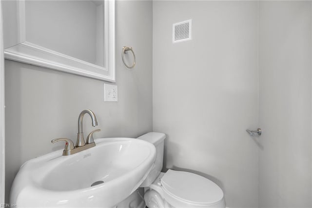 bathroom with visible vents, toilet, and a sink