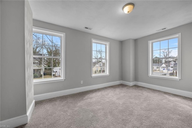 carpeted empty room featuring baseboards and visible vents