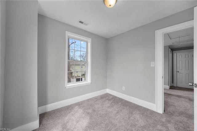 unfurnished room featuring visible vents, carpet floors, baseboards, and attic access