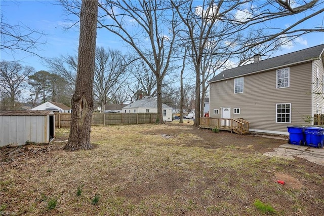 view of yard with an outdoor structure, a storage shed, a deck, and fence