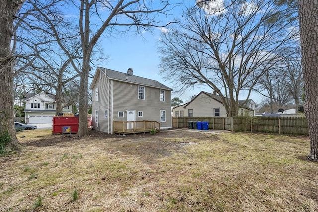 back of property with a deck, a yard, fence, and a chimney