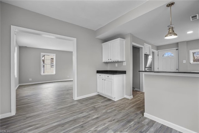 kitchen with dark countertops, stainless steel refrigerator, white cabinets, and baseboards