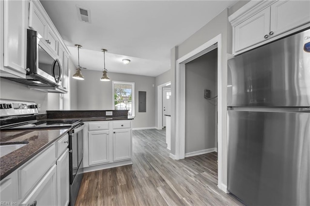 kitchen with wood finished floors, visible vents, a peninsula, stainless steel appliances, and white cabinets